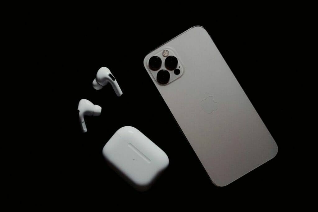 Airpods, Airpod case, and Iphone on black backround.