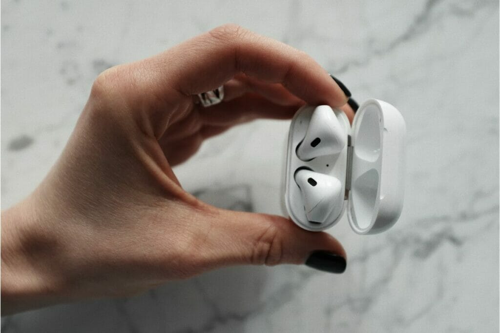Woman's hand holding open airpod case with airpods inside.