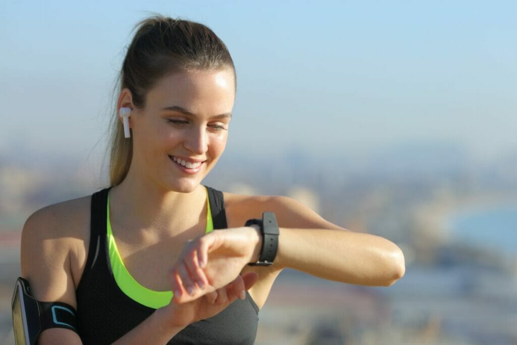 Woman looking at her smartwatch while exercising with bluetooth headset.