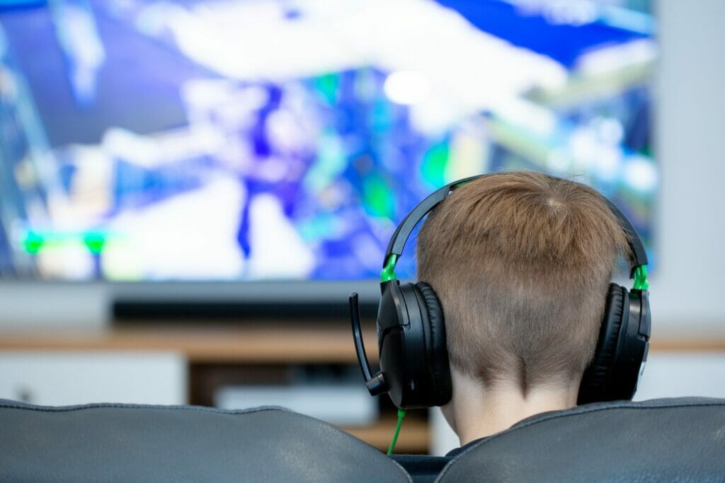 a young boy wearing headphones watching a television