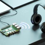 A Raspberry Pi connected wirelessly to Bluetooth headphones with signal waves between them on a clean workspace.