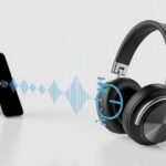 A pair of Bluetooth headphones wirelessly connected to a smartphone with visual sound waves showing a delay between the devices.
