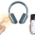 How to Turn on Bluetooth Headphones Without Summoning Tech Support A hand pressing the power button on Bluetooth headphones with a smartphone showing Bluetooth settings nearby.