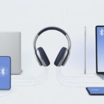 How to Pair Bluetooth Headphones with Multiple Devices Without Losing Your Sanity A pair of Bluetooth headphones connected wirelessly to a smartphone, laptop, and tablet around it.