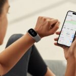 How to use a fitness tracker with Polar Flow Without Breaking a Sweat (Or Your Tracker) A person wearing a fitness tracker on their wrist looks at a smartphone showing fitness data and graphs.