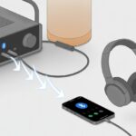 An illustration showing Bluetooth headphones wirelessly connected to an amplifier with a smartphone nearby displaying Bluetooth settings.