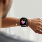 Close-up of a wrist wearing a smartwatch showing a heart rate monitoring screen with a heart icon and pulse graph.