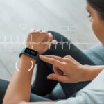 A person wearing a fitness tracker on their wrist, using it to take an ECG reading.