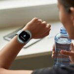 How to use a smartwatch for hydration reminders and finally stop pretending coffee counts as water A person wearing a smartwatch with a hydration reminder icon on the screen, holding a water bottle indoors.