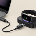 A fitness tracker properly connected to a charging dock with a visible battery icon indicating it is charging.
