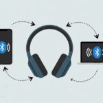 How to Switch Bluetooth Headphones Between Devices Without Losing Your Sanity A pair of Bluetooth headphones between a smartphone and a laptop with arrows showing connection switching.