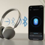 Why do my Bluetooth headphones not connect to iPhone? Seriously, Did They Have a Fight? An iPhone and Bluetooth headphones on a desk with fading wireless signals between them indicating a failed connection.