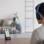 How to extend Bluetooth headphone range and stop pacing like a lost puppy A person wearing Bluetooth headphones connected wirelessly to a smartphone with signal waves extending farther thanks to a Bluetooth signal range extender device placed between them.